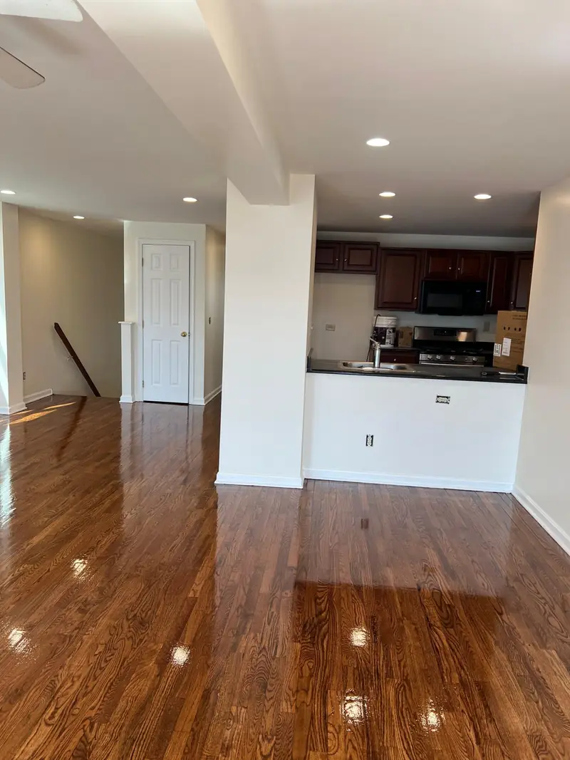 Open living area with refinished glossy hardwood floor leading to the kitchen