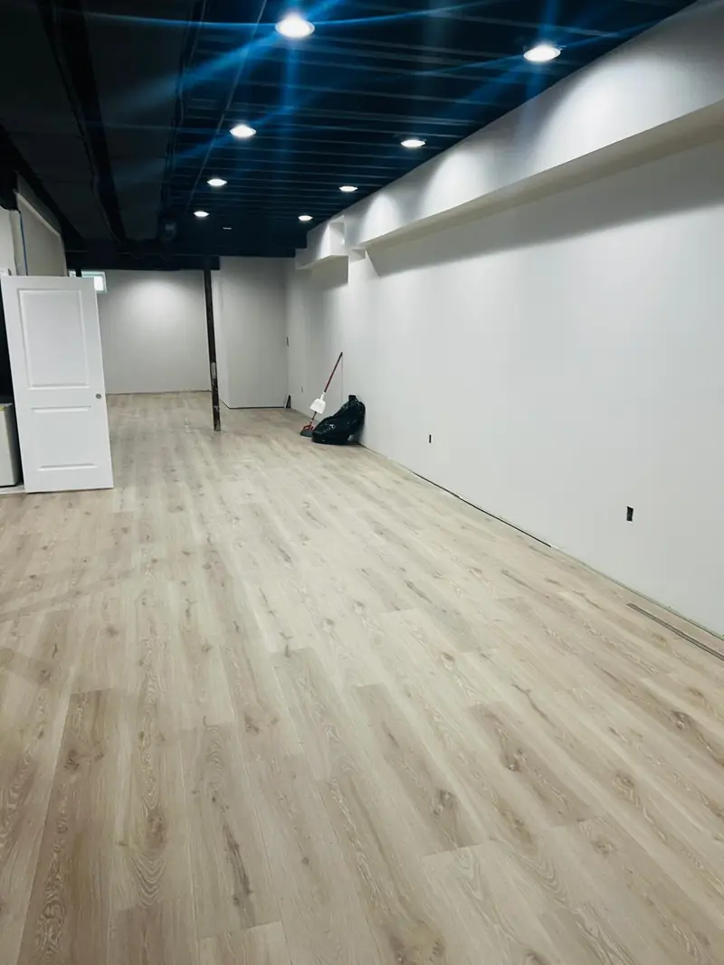 Long basement with light vinyl plank flooring installed wall to wall