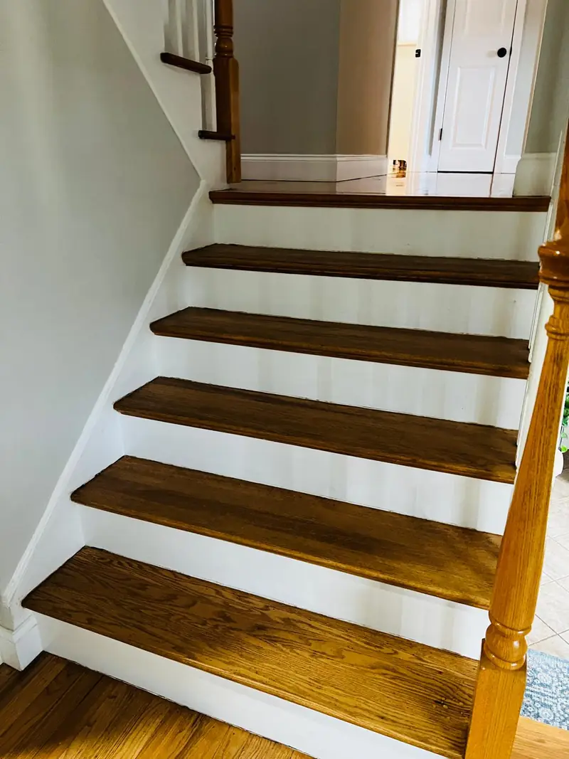Staircase with stained hardwood treads and white risers after refinishing
